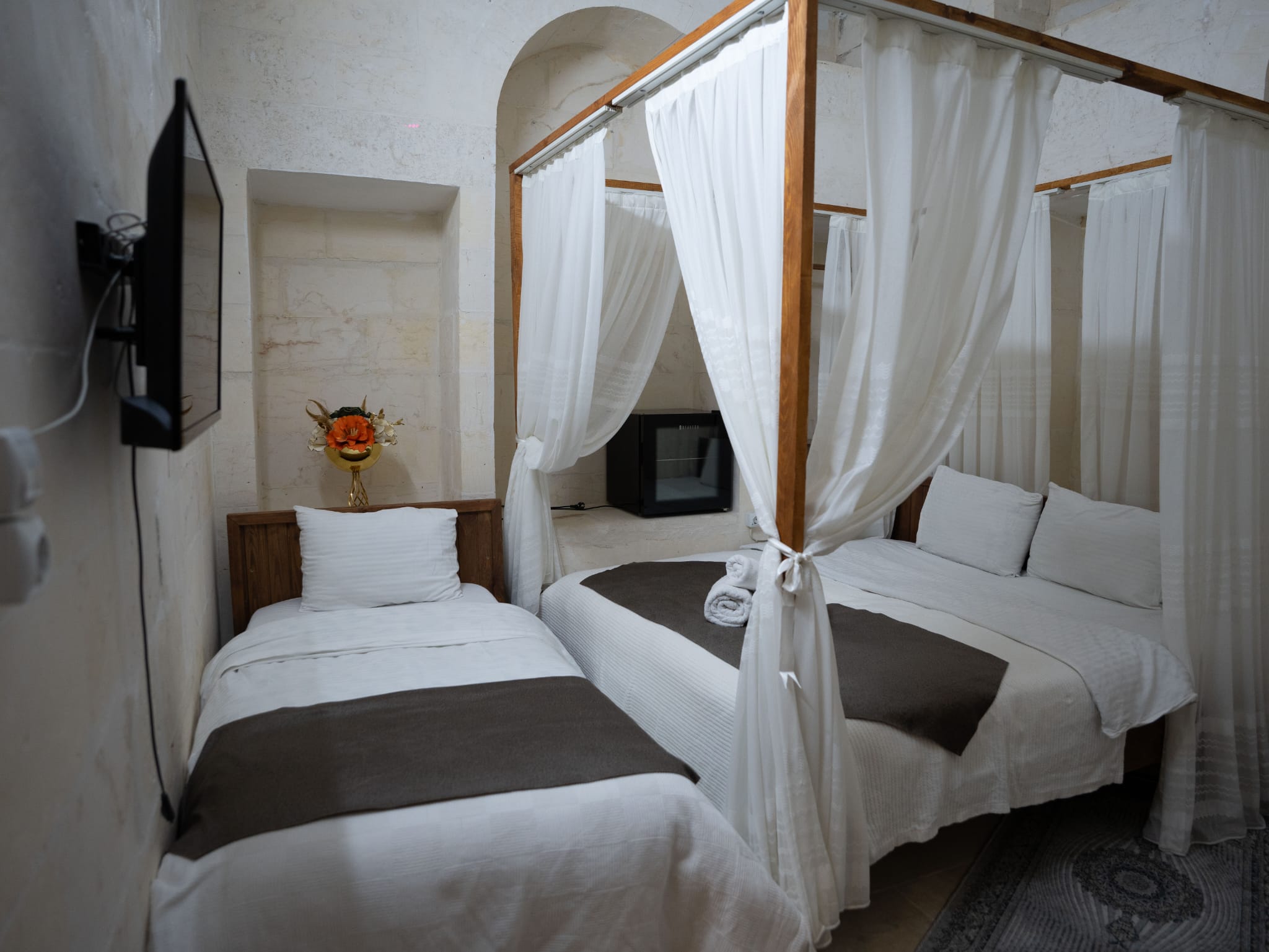 Otel odasında yatak ve taş duvar detayı